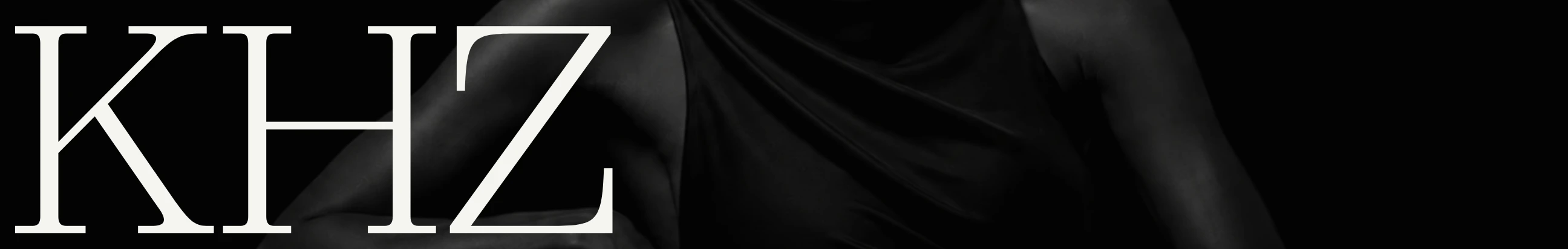 Monochrome high-fashion hero header with oversized serif typography superimposed over low-key editorial portrait photography.