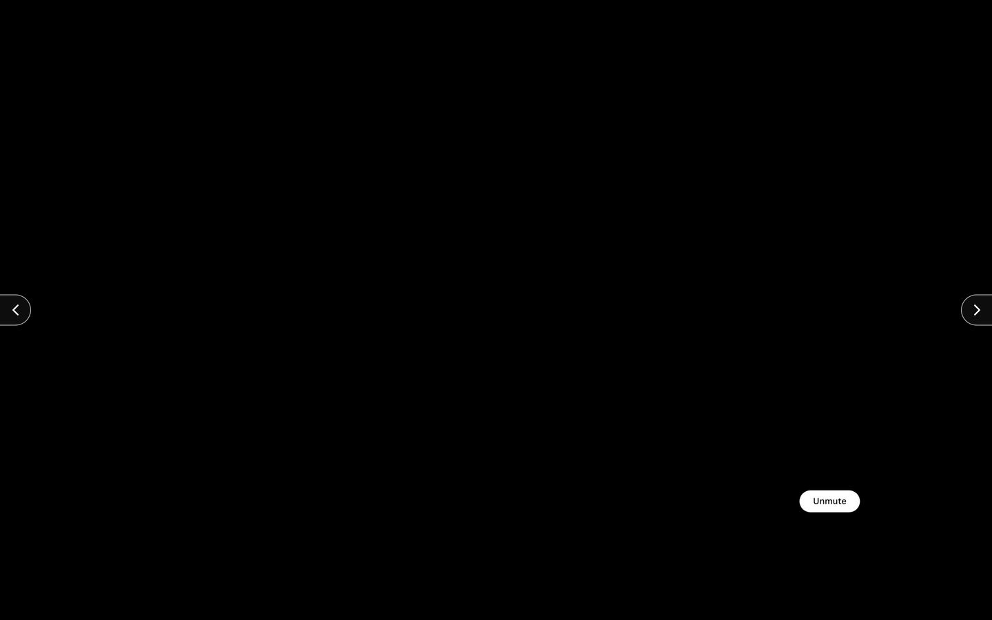 A pitch-black full-screen video stage suspended in silence, punctuated only by minimal navigation arrows and an unmute pill.