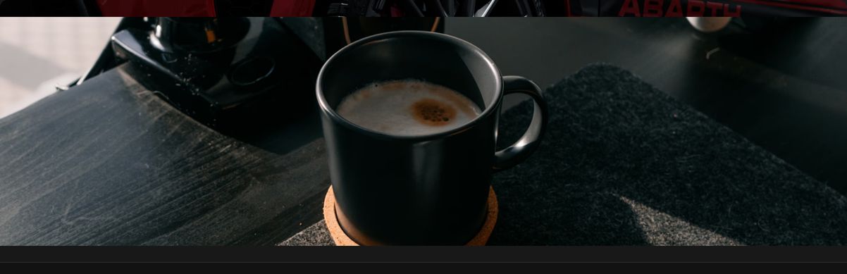 A quiet visual break featuring an atmospheric close-up photograph of a dark ceramic coffee mug on a desk.