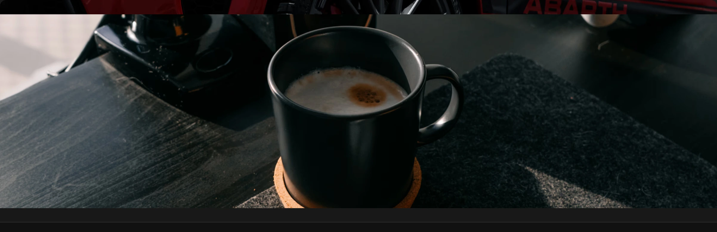 A quiet visual break featuring an atmospheric close-up photograph of a dark ceramic coffee mug on a desk.