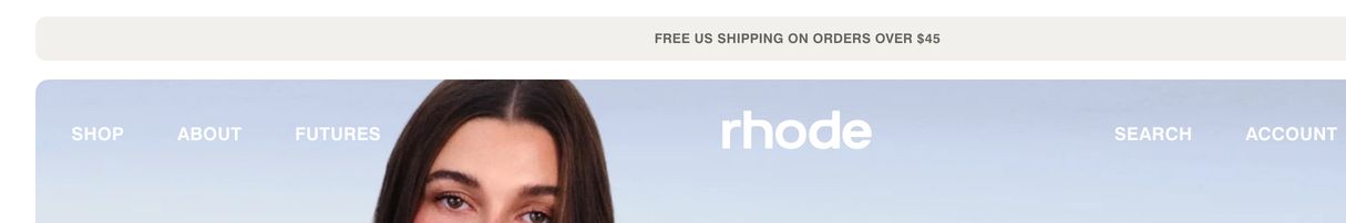 Clean, muted e-commerce header with a pale announcement pill and transparent uppercase navigation floating over lifestyle photography.