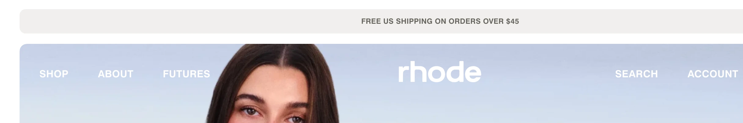 Clean, muted e-commerce header with a pale announcement pill and transparent uppercase navigation floating over lifestyle photography.