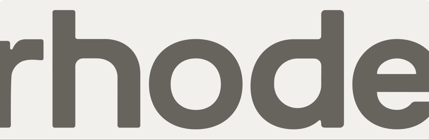A gigantic, muted grey brand wordmark bleeding past the frame on a soft warm off-white canvas.
