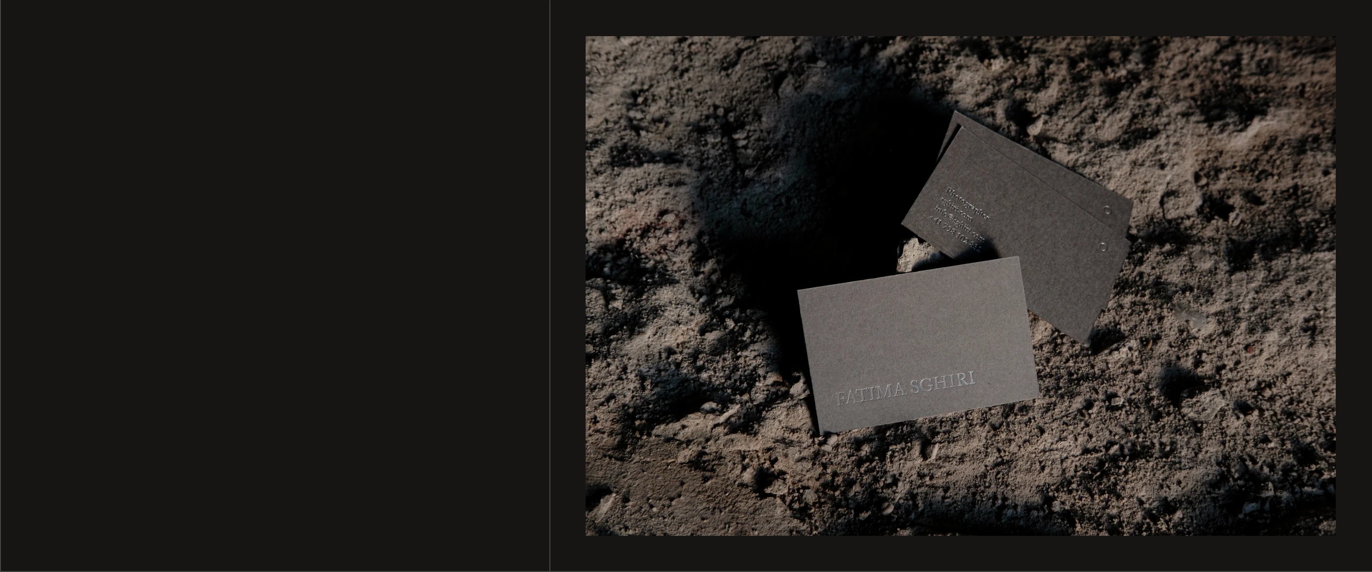 Somber, tactile branding showcase featuring embossed stationery resting on rough earthen ground beside a solid dark void.
