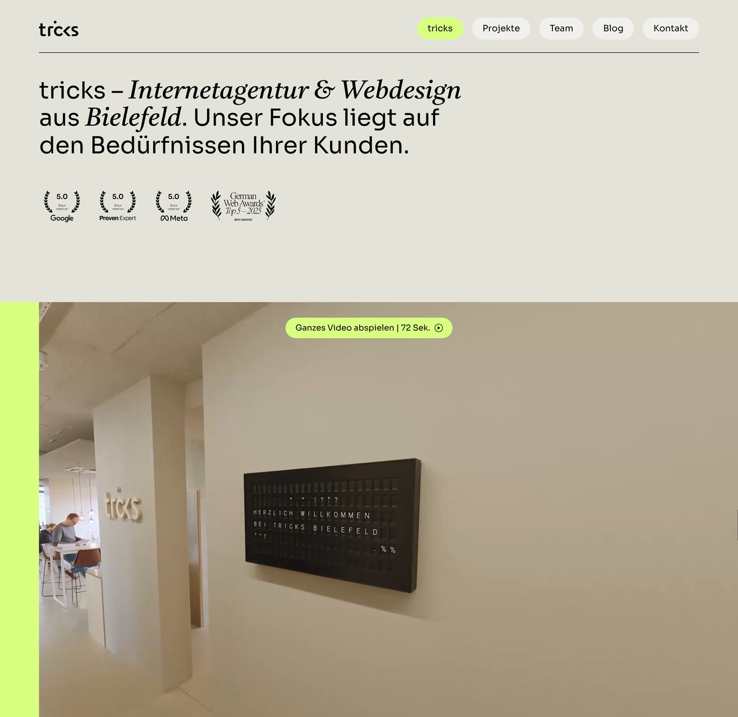 Warm editorial agency hero pairing refined mixed typography with trust badges and an embedded office video.
