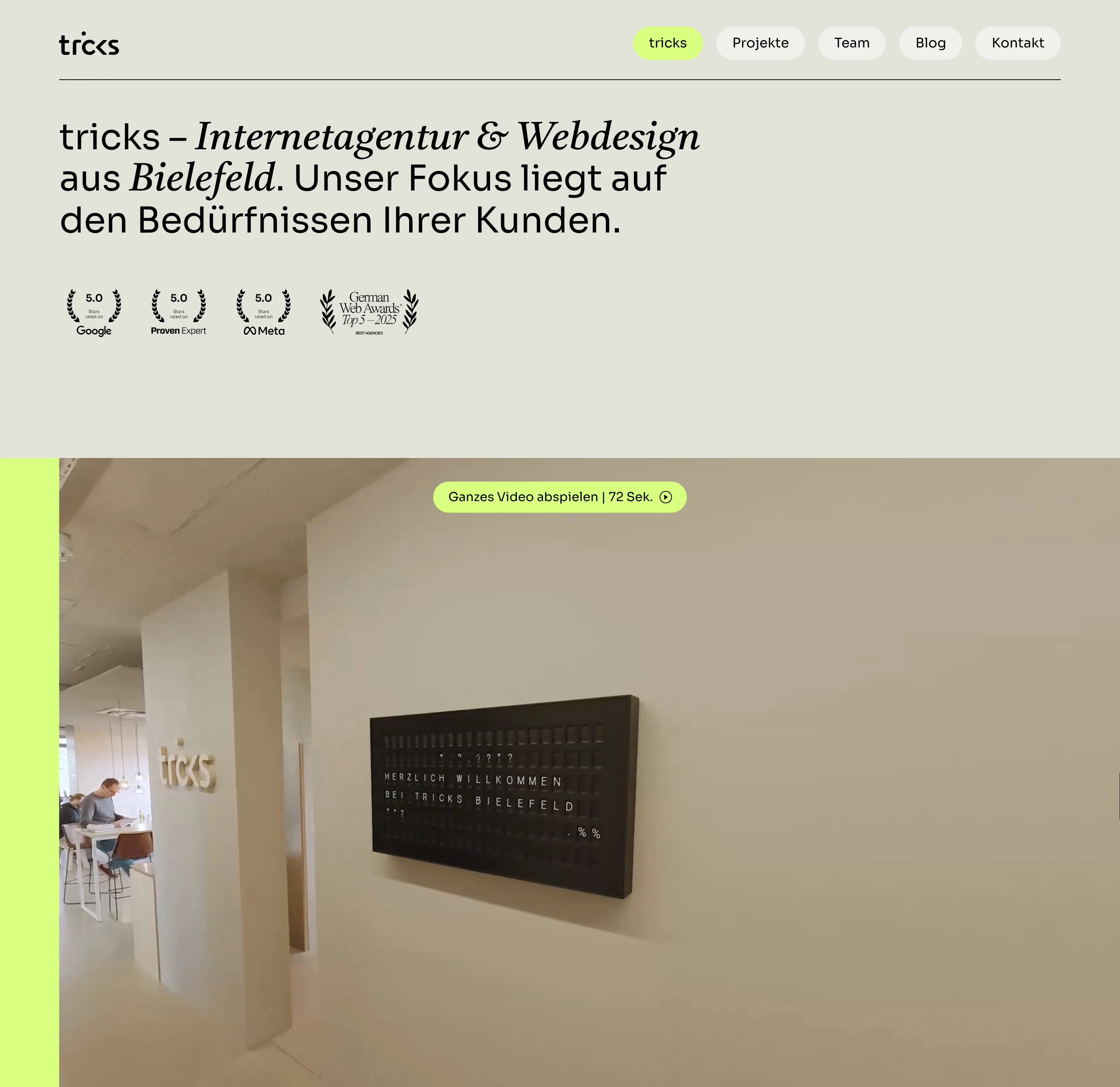 Warm editorial agency hero pairing refined mixed typography with trust badges and an embedded office video.