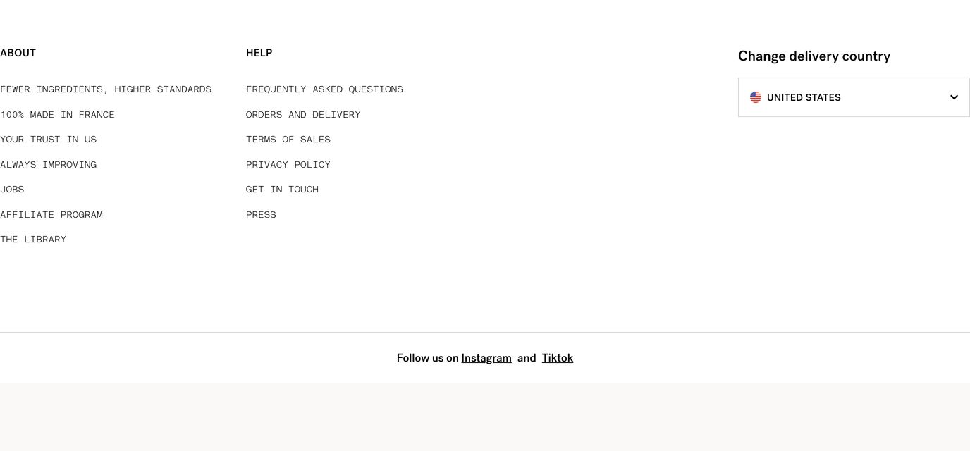 An airy, minimalist monochrome footer organized into sparse uppercase link columns and a country selector.
