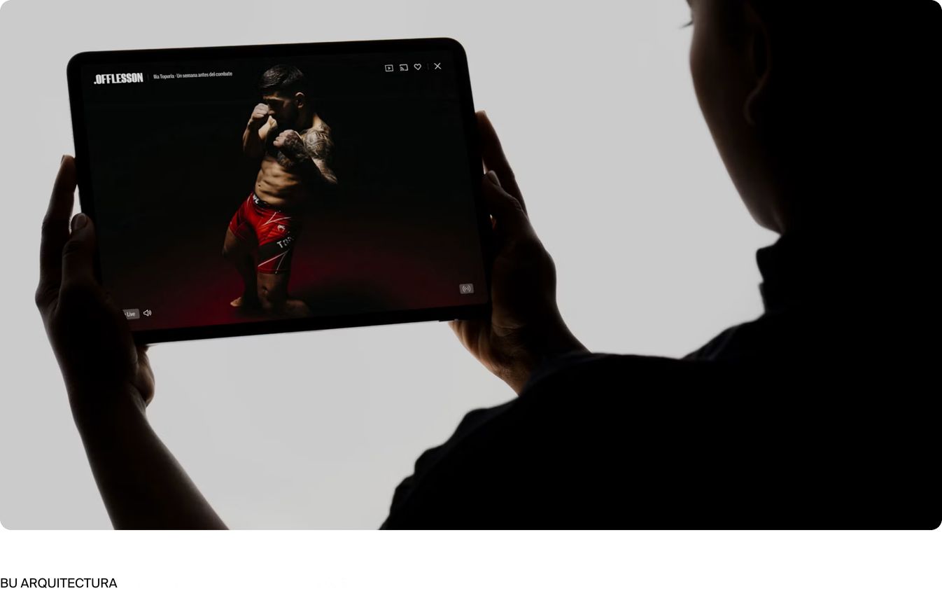 Dramatic chiaroscuro studio photography of hands holding a tablet showcasing digital video work in a stark minimal layout.